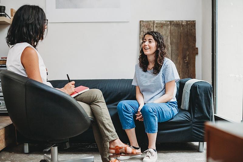 two women sitting on a couch talking