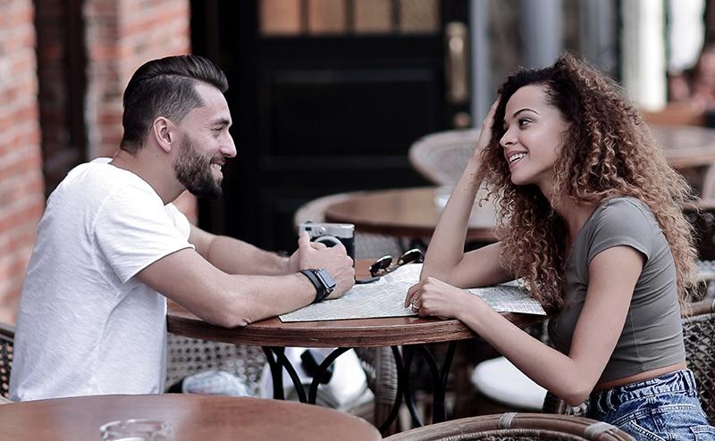 Young couple laying on their backs on pavement looking up at camera with smiles.